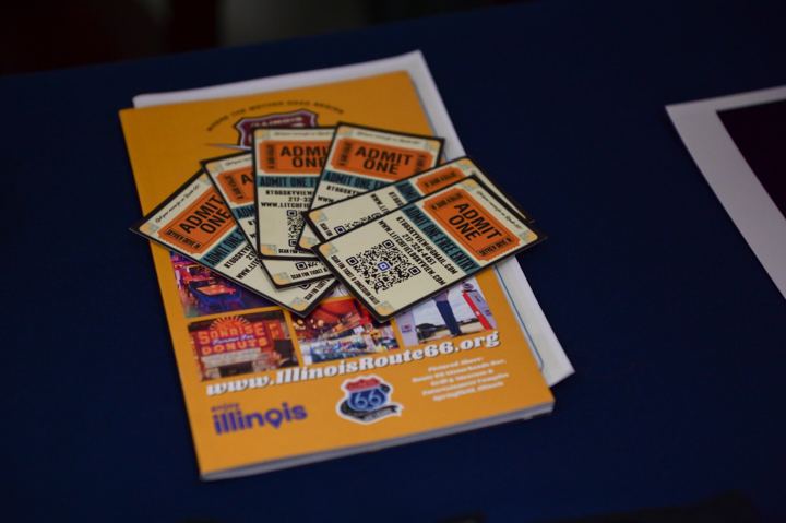 Admit One tickets scattered across Illinois Route 66 brochures on the festival welcome table.